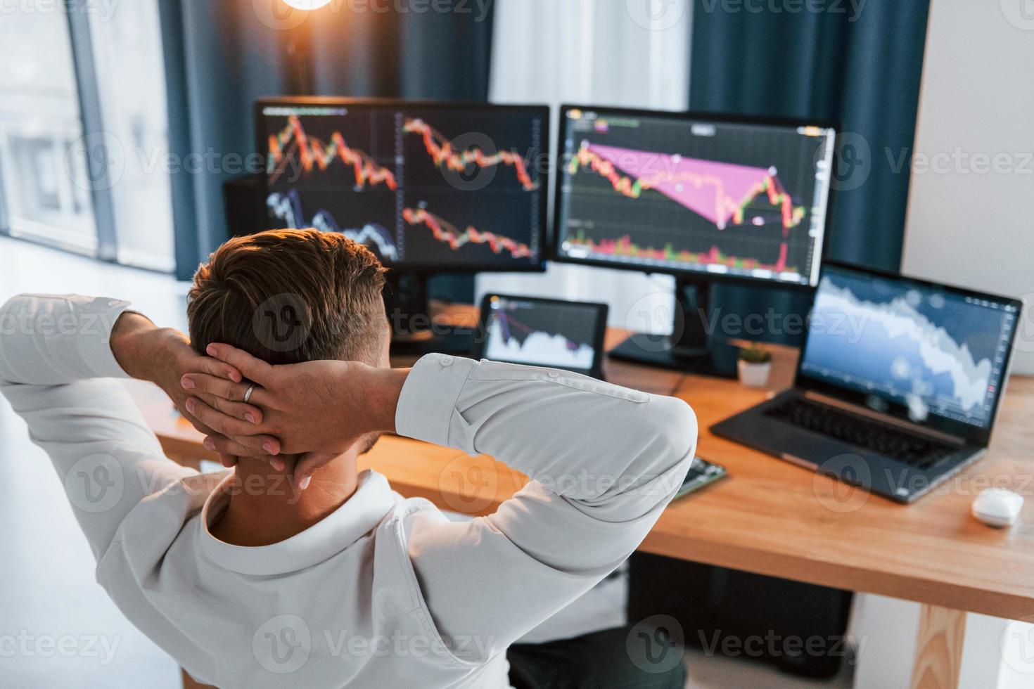 Taking a rest. Young businessman in formal clothes is in office with multiple screens photo