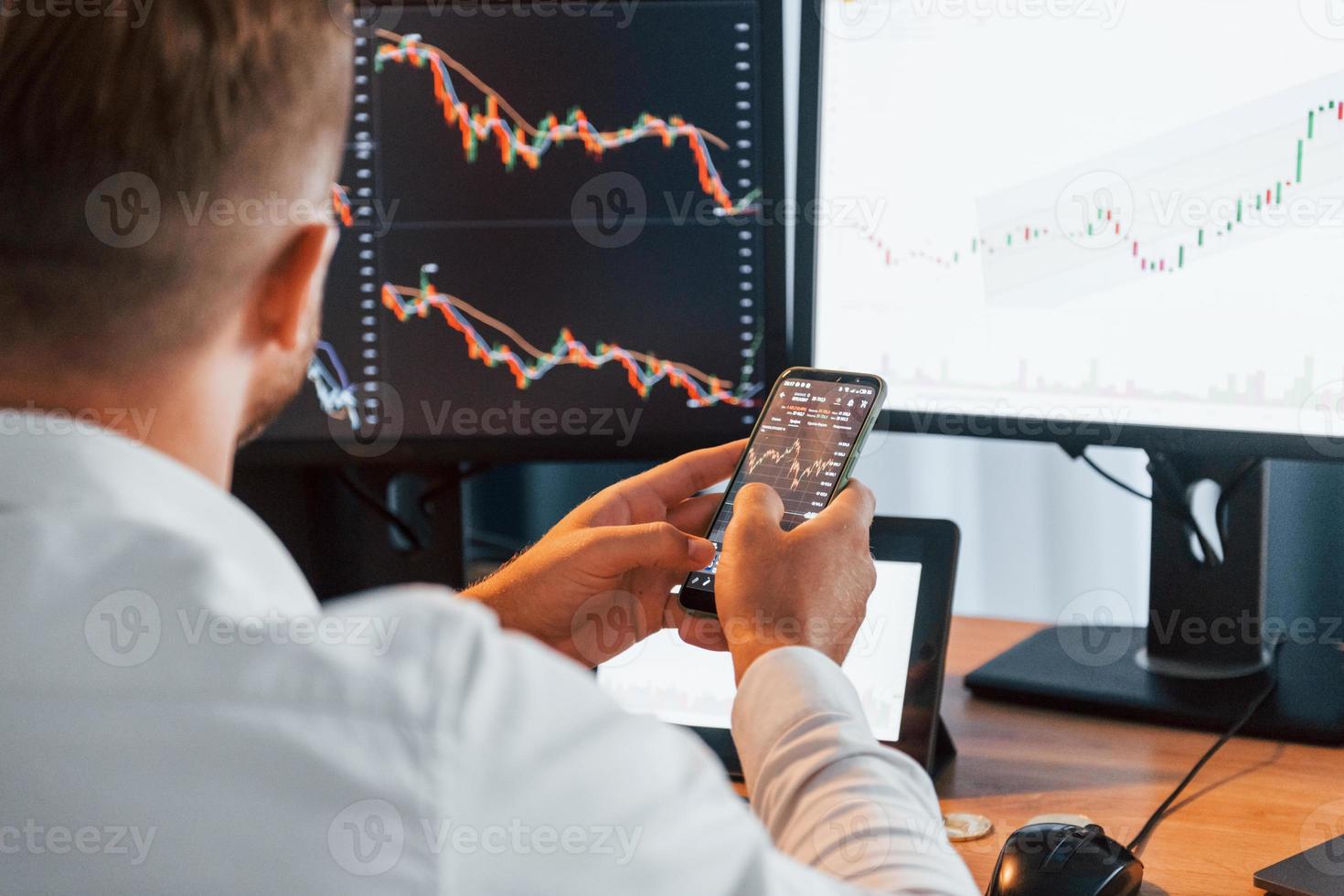 Graphs and diagrams. Young businessman in formal clothes is in office with multiple screens photo