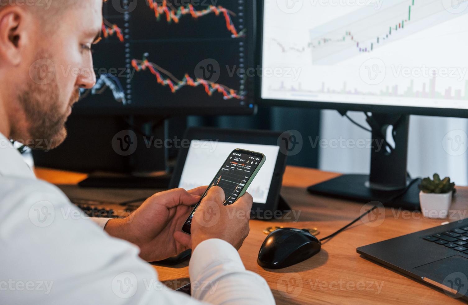 Graphs and diagrams. Young businessman in formal clothes is in office with multiple screens photo