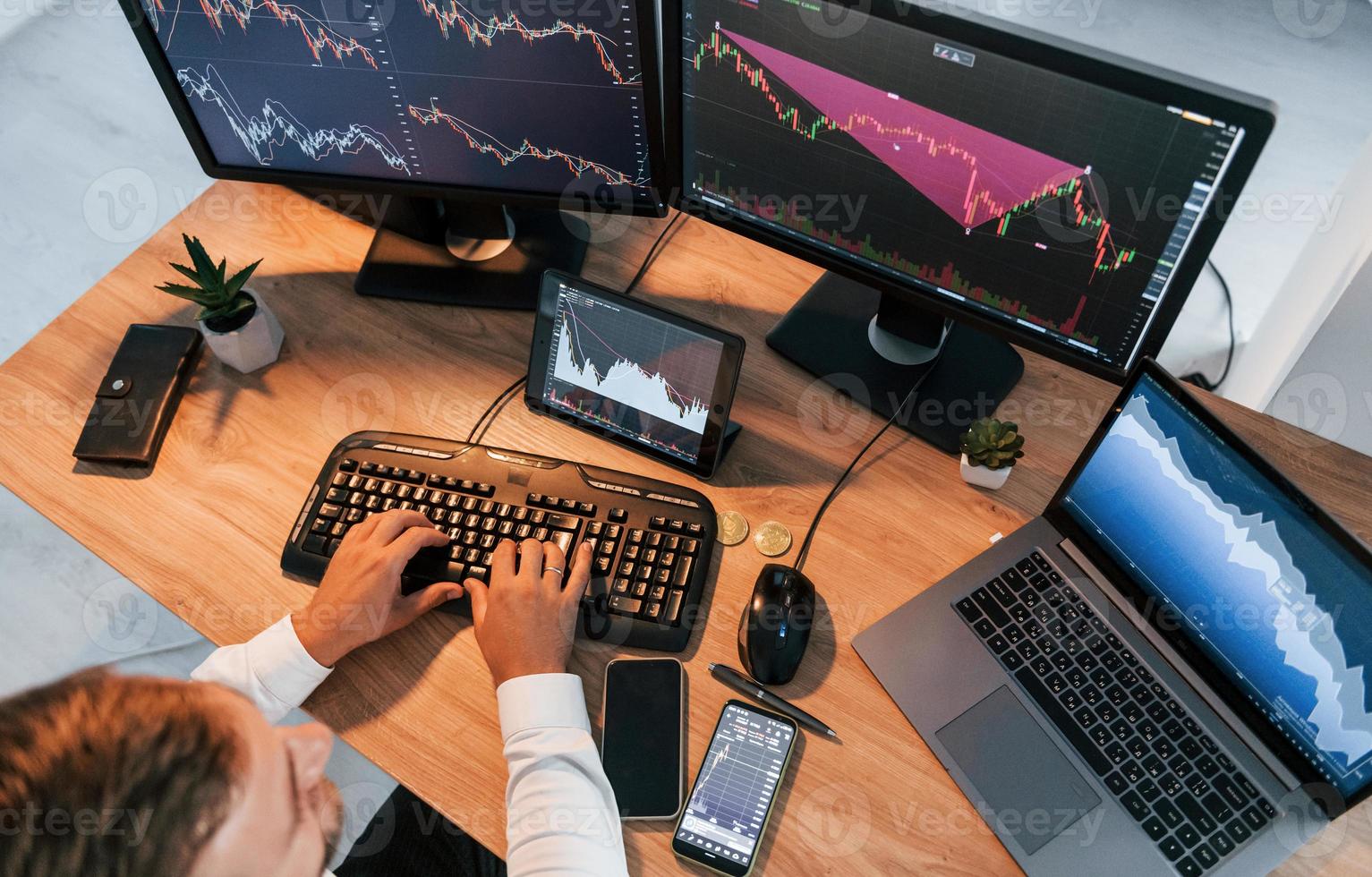 Close up view. Young businessman in formal clothes is in office with multiple screens photo