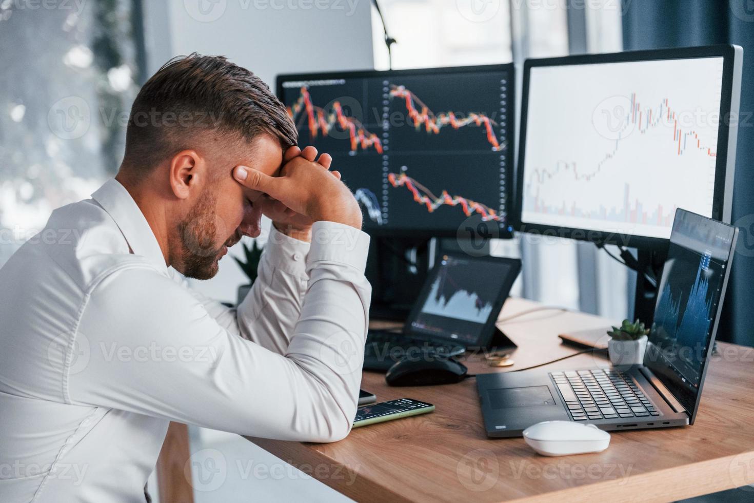 Focusing on the work. Young businessman in formal clothes is in office with multiple screens photo