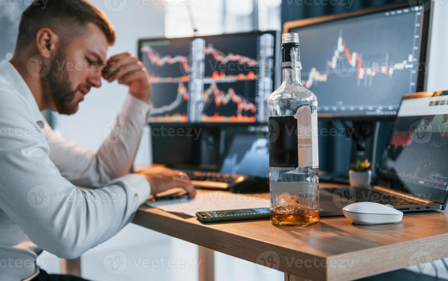 Hard working. Young businessman in formal clothes is in office with multiple screens photo