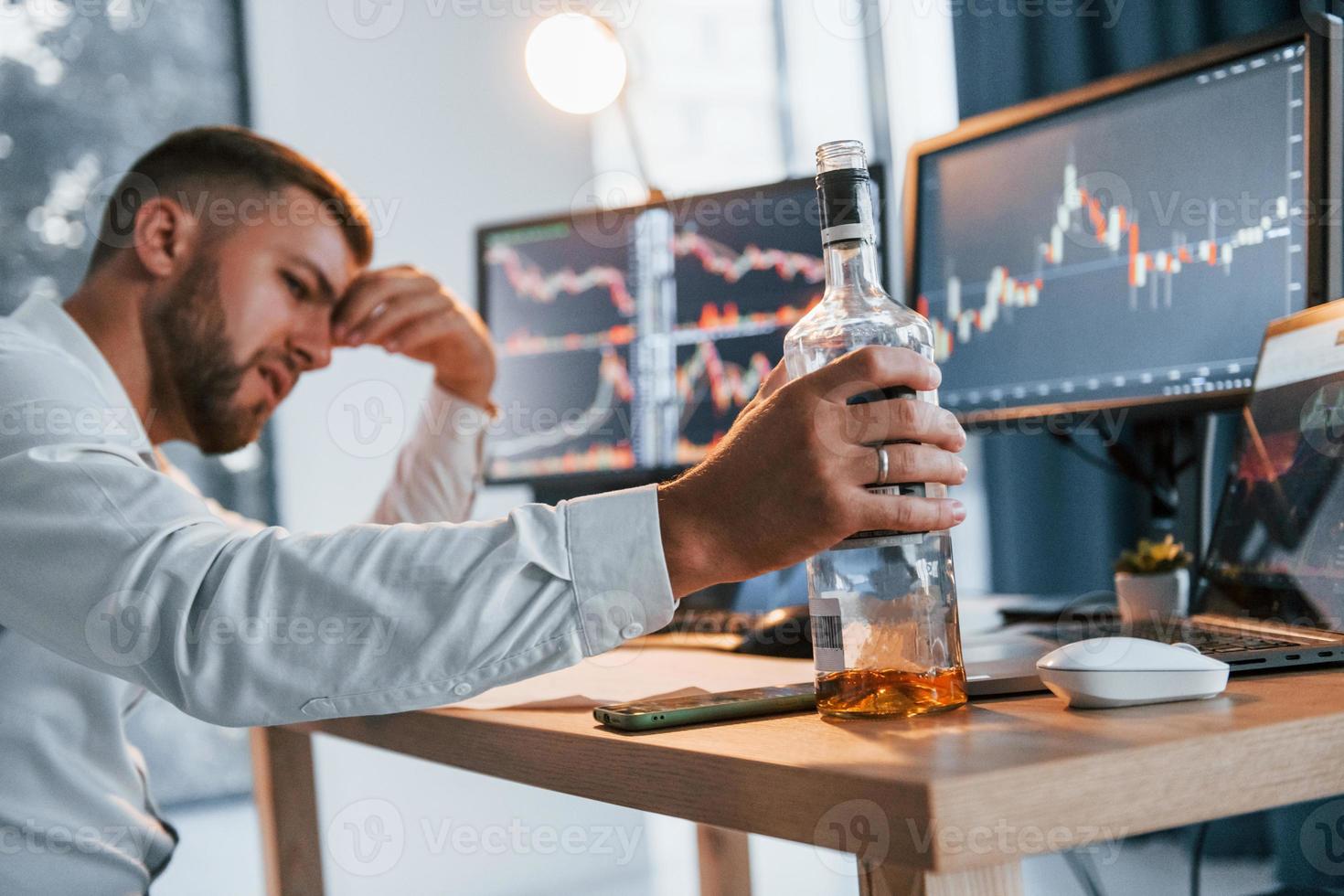 Hard working. Young businessman in formal clothes is in office with multiple screens photo