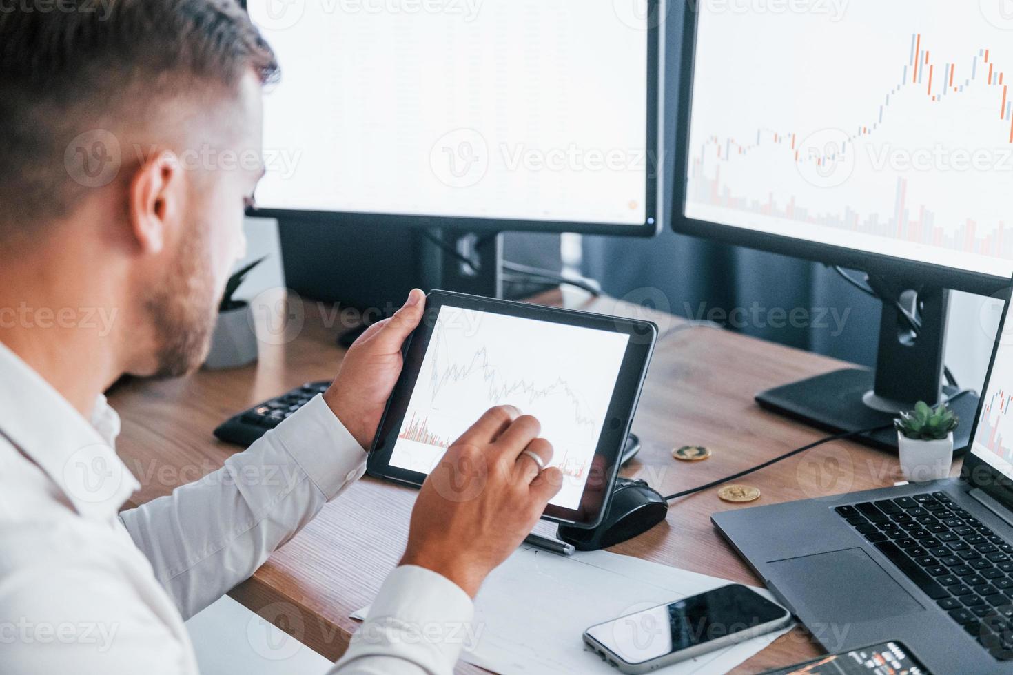 Modern technologies. Young businessman in formal clothes is in office with multiple screens photo