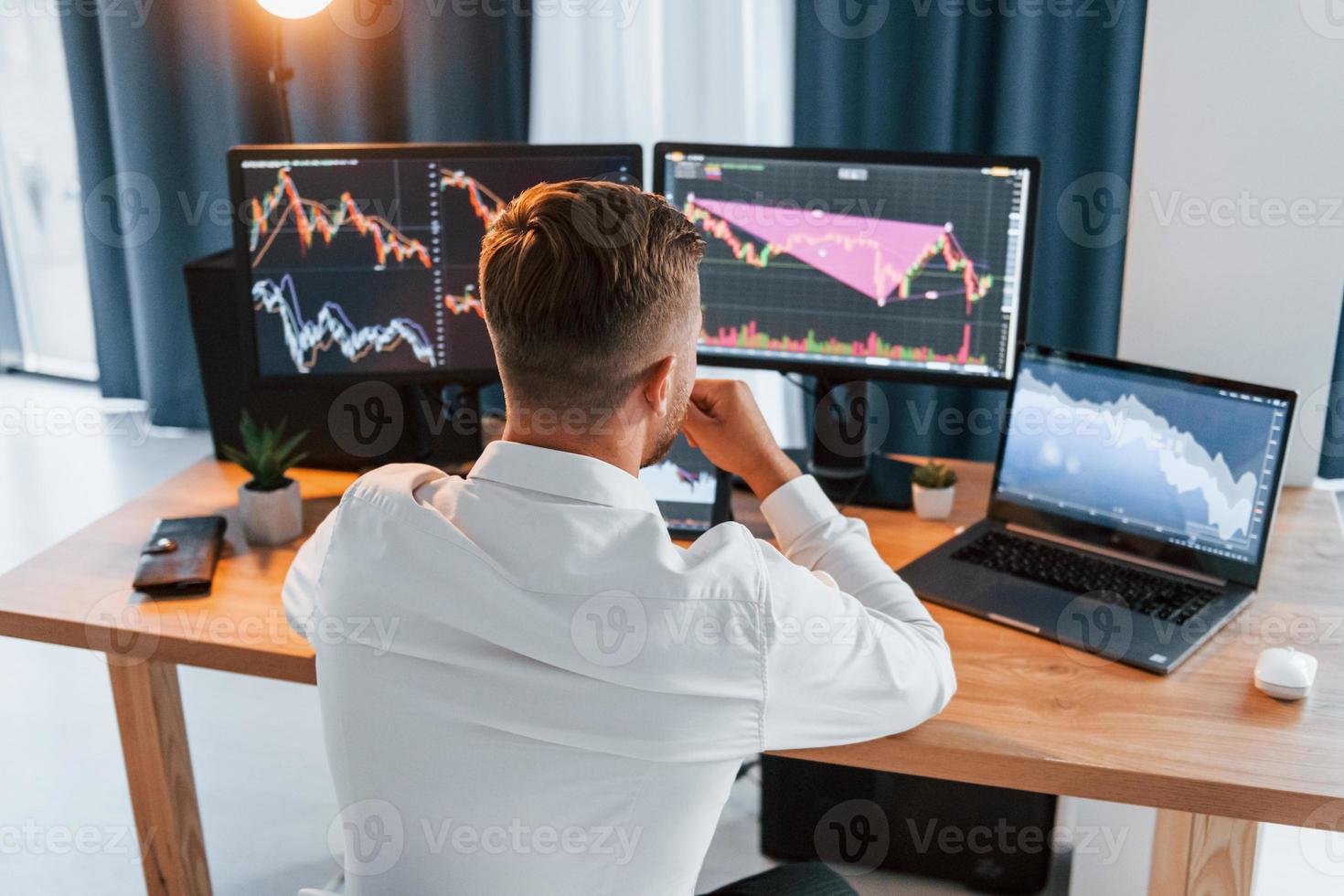 Taking a rest. Young businessman in formal clothes is in office with multiple screens photo