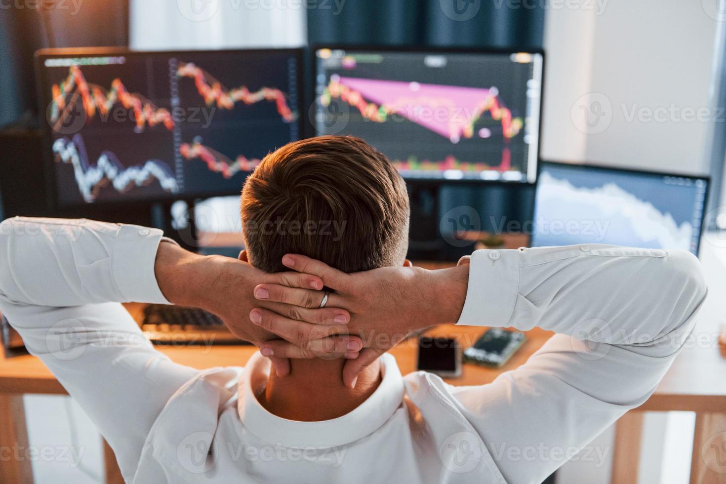 Taking a rest. Young businessman in formal clothes is in office with multiple screens photo