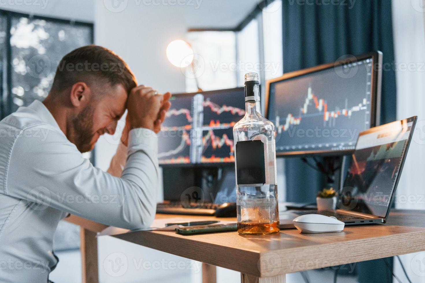 Conception of failure. Young businessman in formal clothes is in office with multiple screens photo