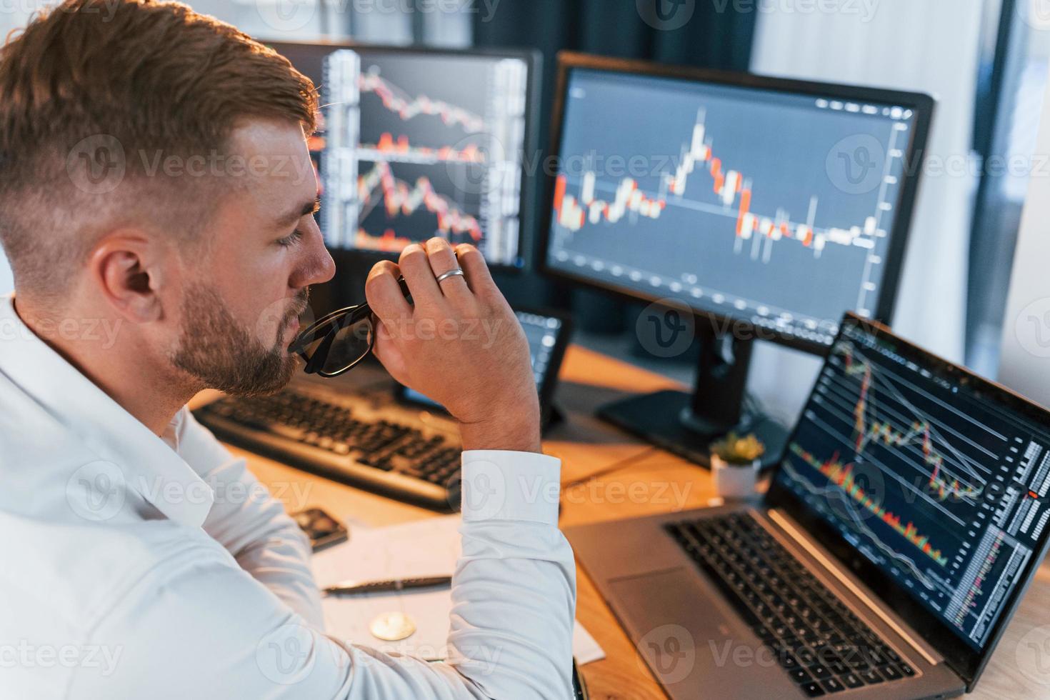 Analyzing information. Young businessman in formal clothes is in office with multiple screens photo