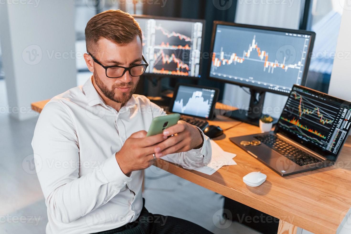 Many monitors. Young businessman in formal clothes is in office with multiple screens photo