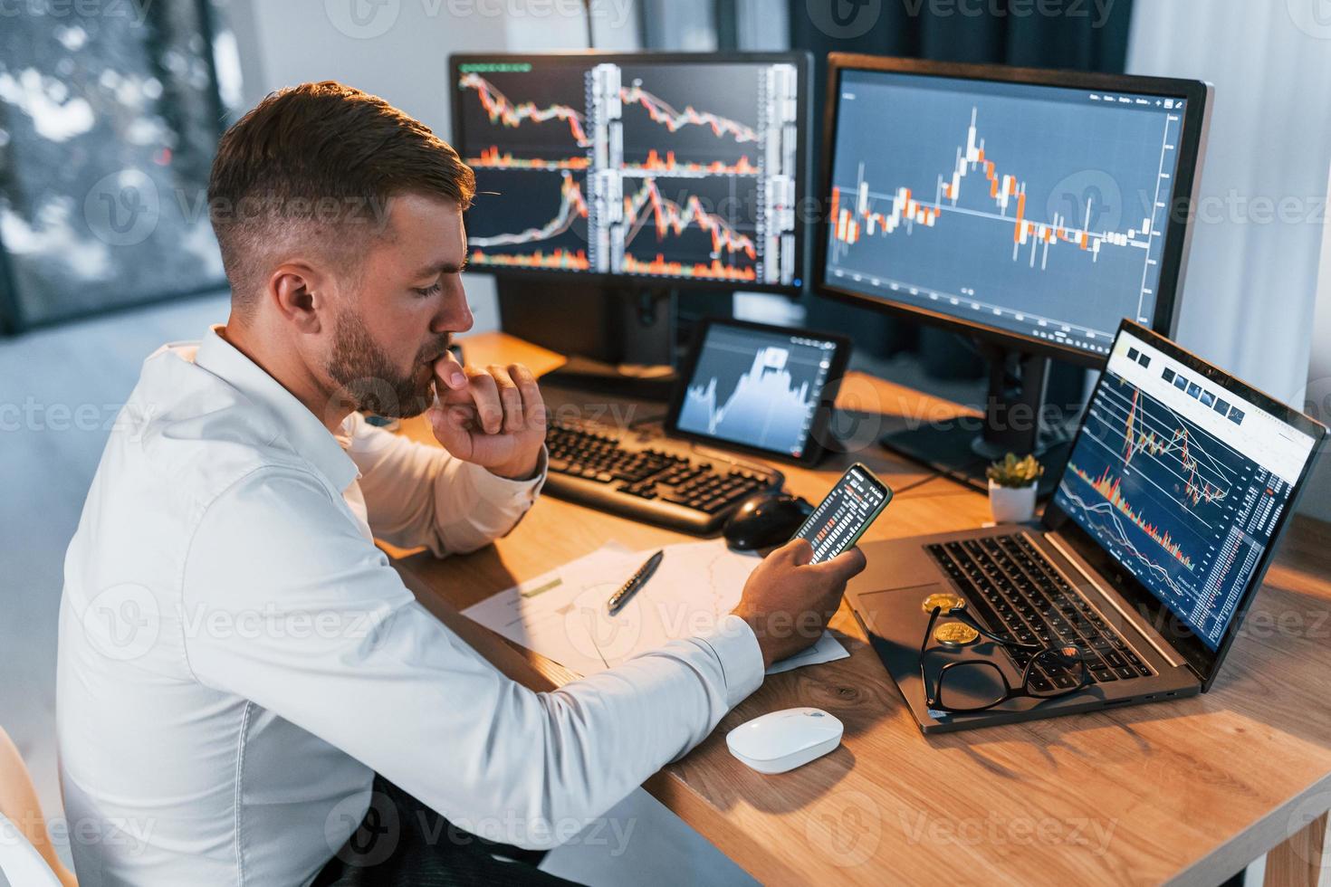 Side view. Young businessman in formal clothes is in office with multiple screens photo