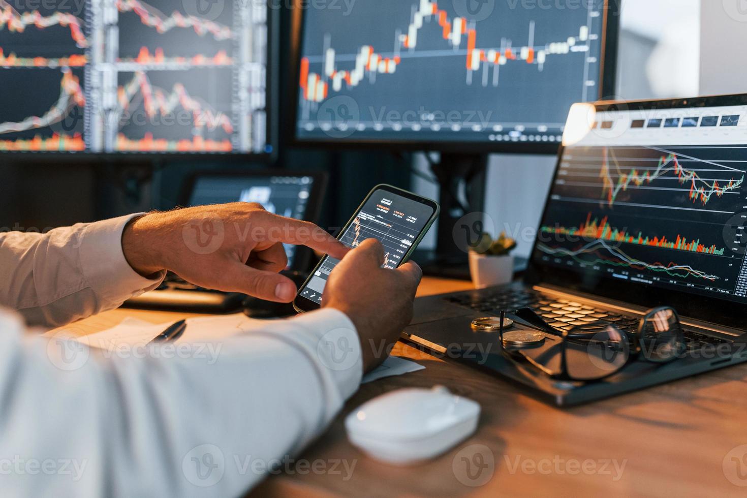 Side view. Young businessman in formal clothes is in office with multiple screens photo