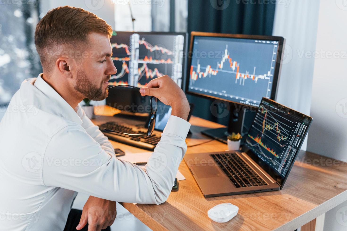 Analyzing information. Young businessman in formal clothes is in office with multiple screens photo