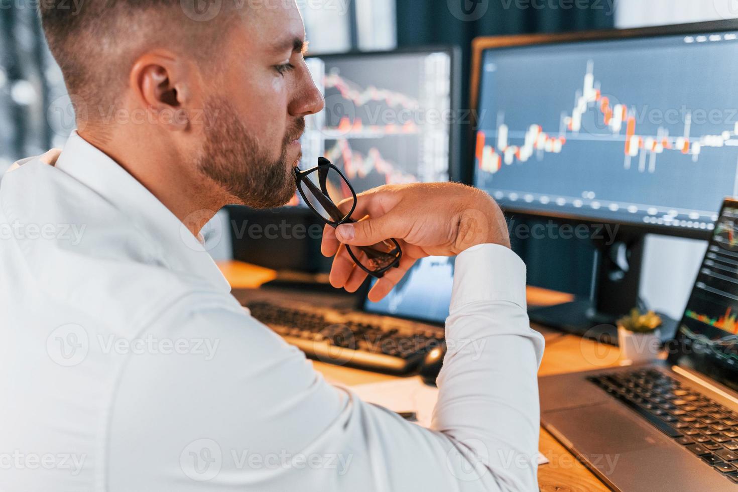 Analyzing information. Young businessman in formal clothes is in office with multiple screens photo