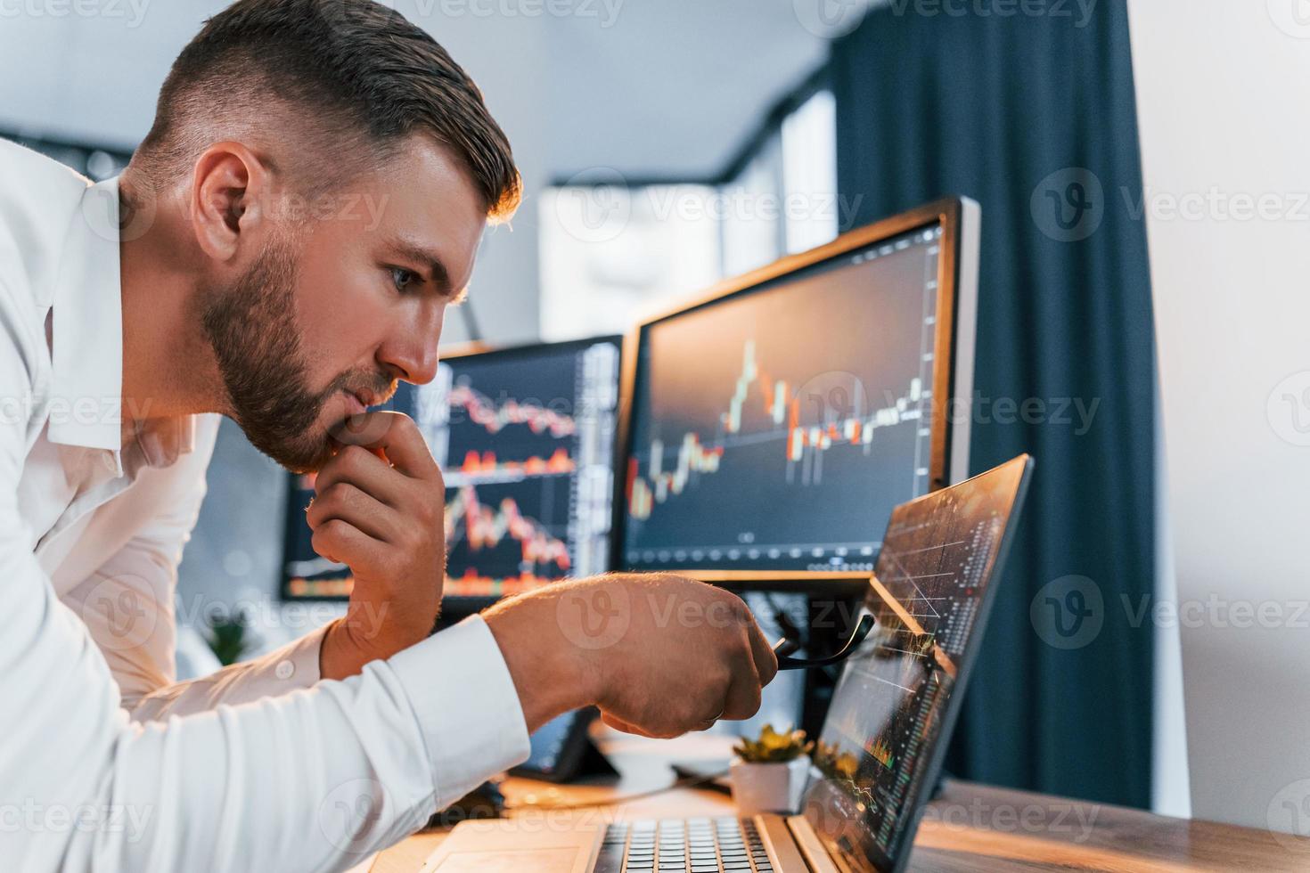 Analyzing information. Young businessman in formal clothes is in office with multiple screens photo