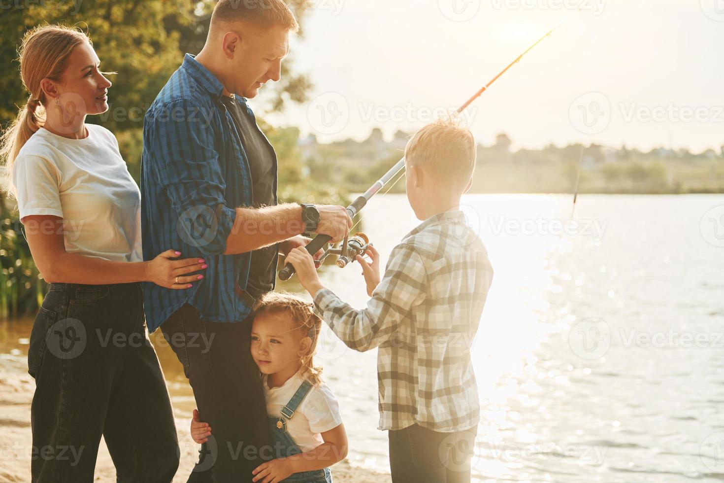 Conception of vacation. Father and mother with son and daughter on fishing together outdoors at summertime photo