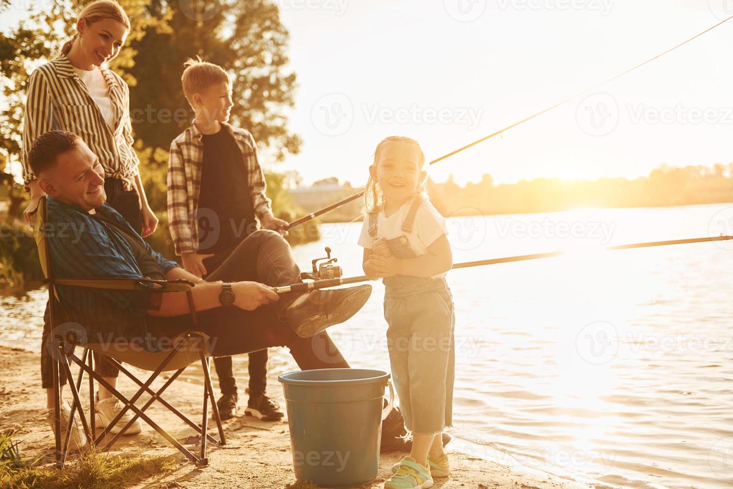 Beautiful nature. Father and mother with son and daughter on fishing together outdoors at summertime photo