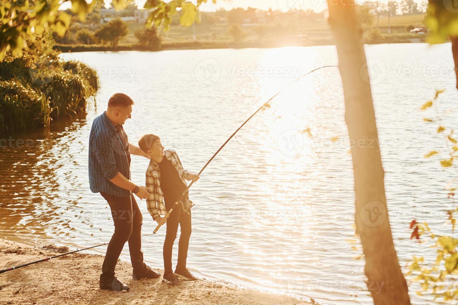 With catch. Father and son on fishing together outdoors at summertime photo