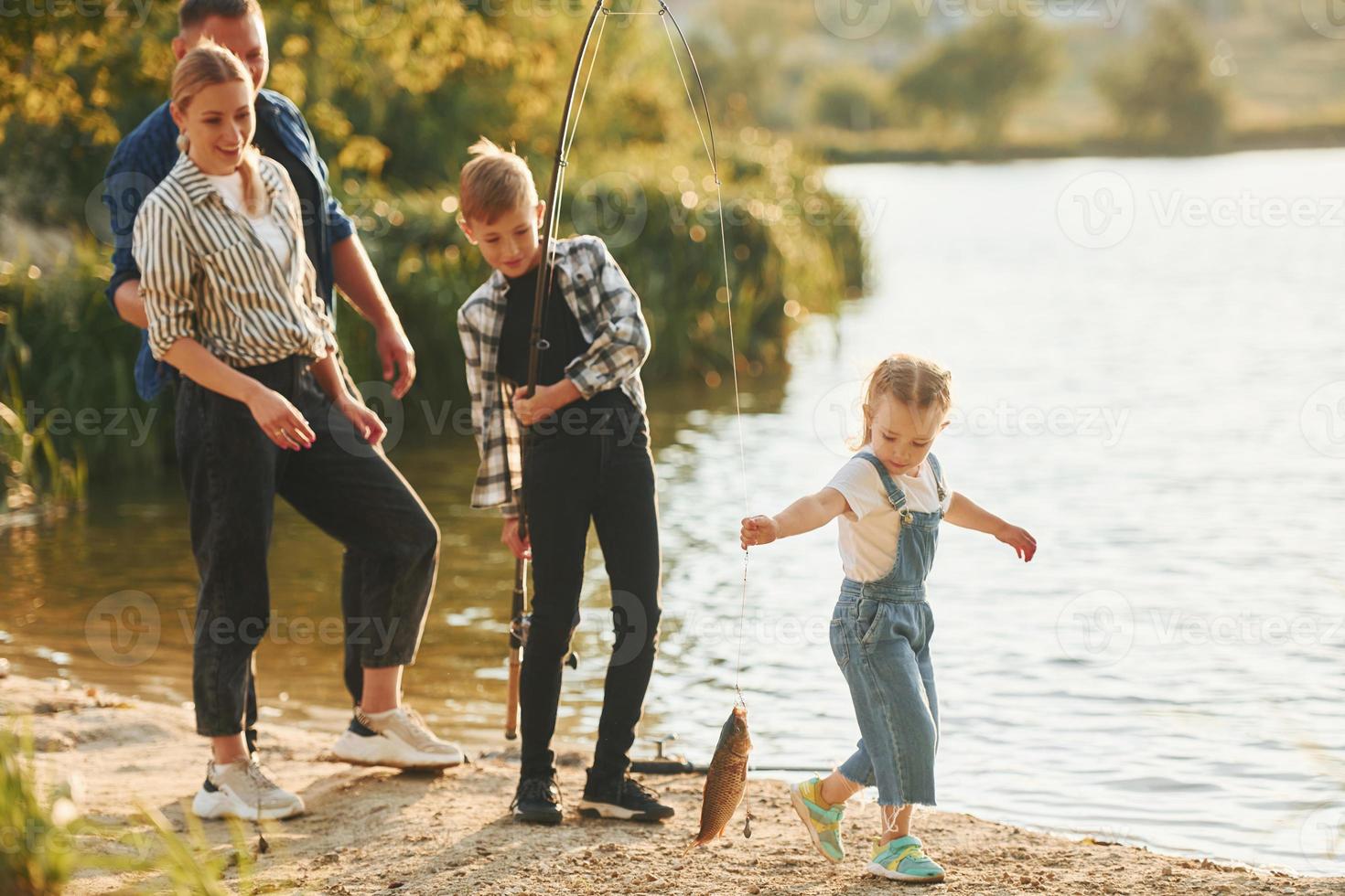 Weekend activities. Father and mother with son and daughter on fishing together outdoors at summertime photo