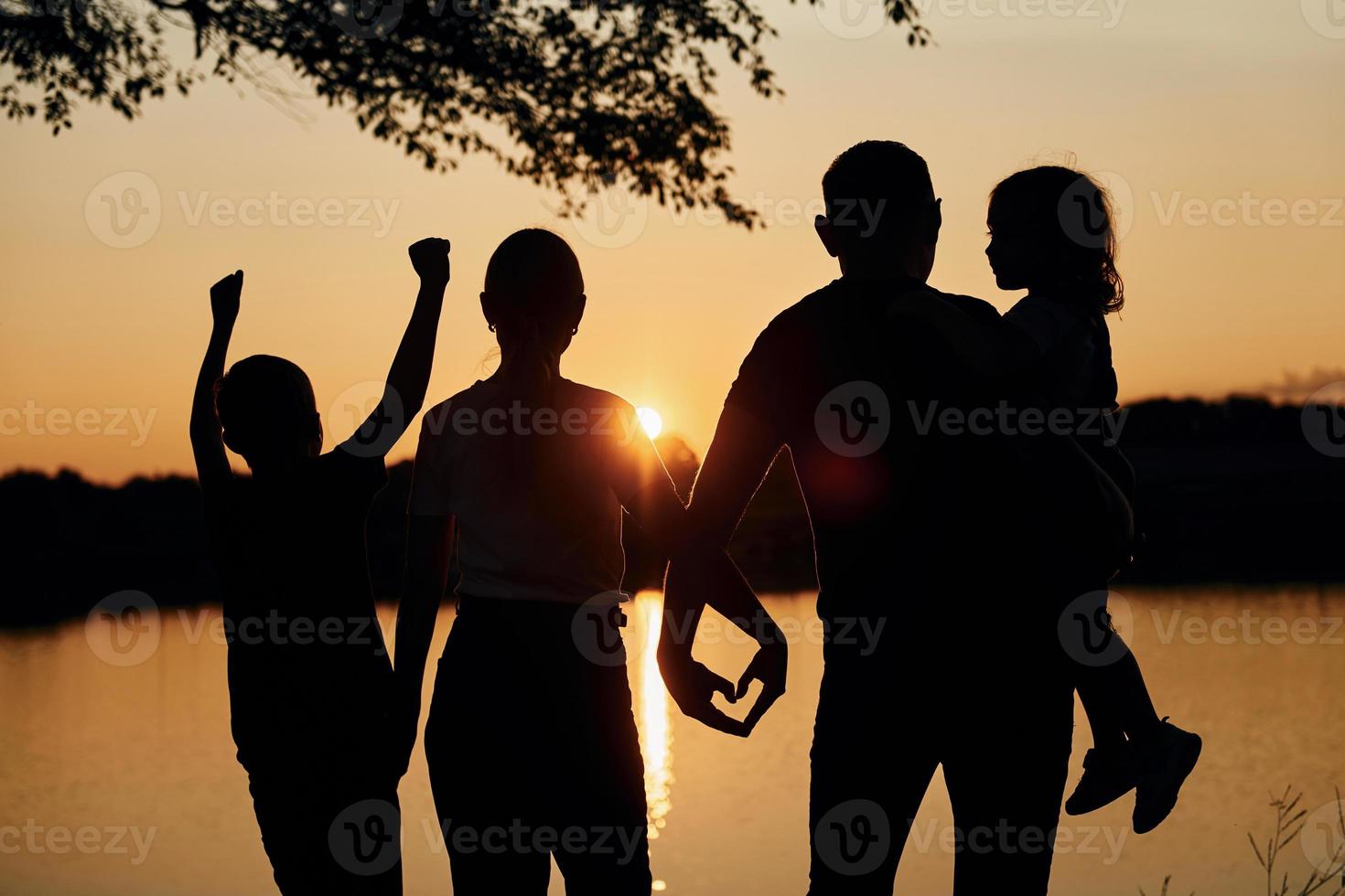 Looking at sunset. Family of mother, father and kids is on the camping photo