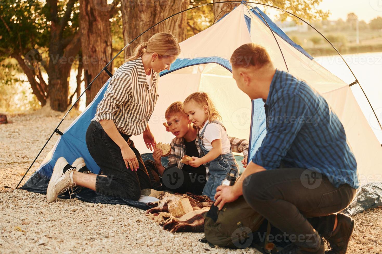 Sitting on the ground. Family of mother, father and kids is on the camping photo