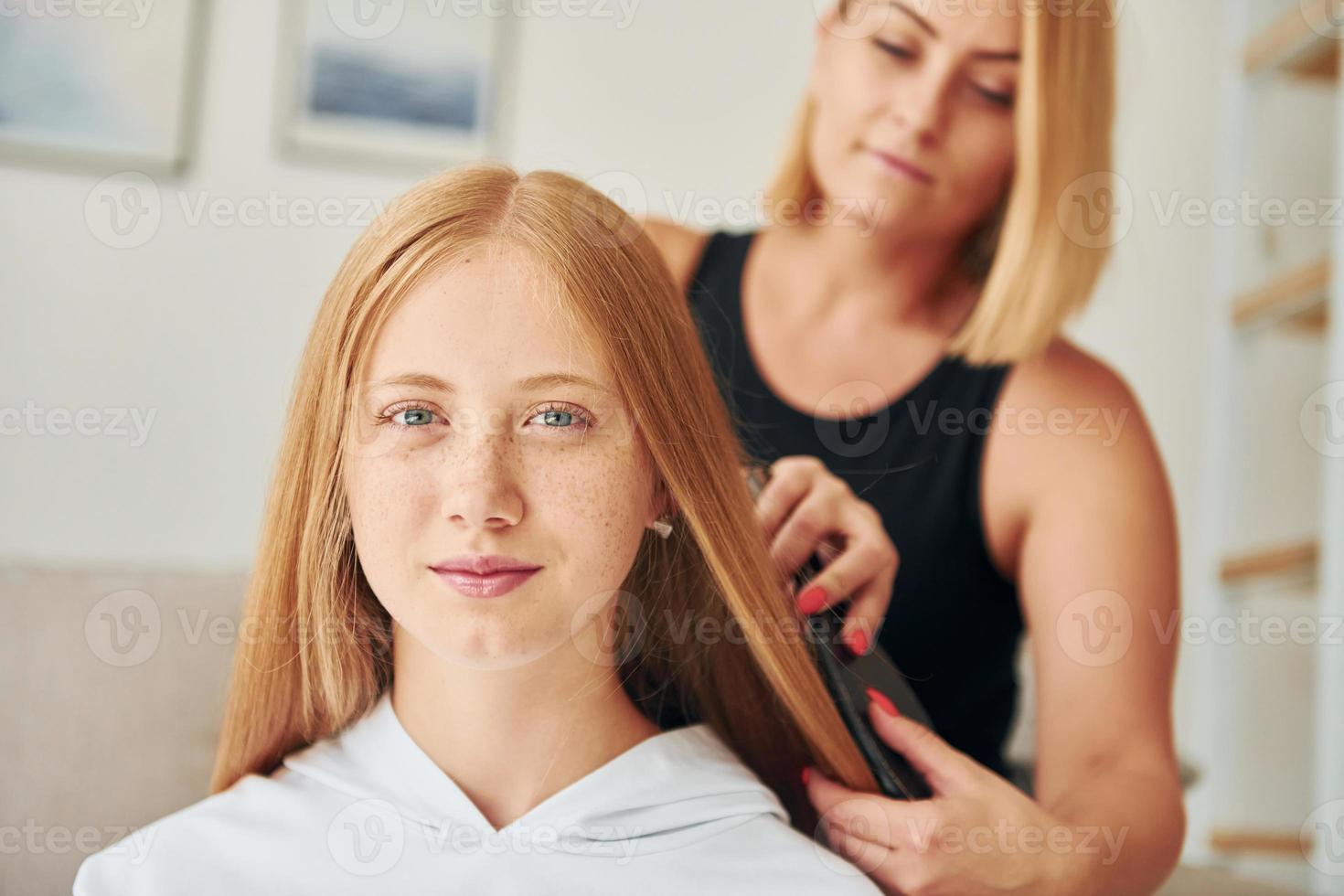 haciendo peinado. una adolescente con su madre está en casa durante el día foto