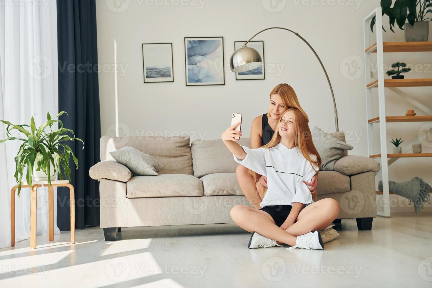 Sitting on the floor. Female teenager with her mother is at home at daytime photo