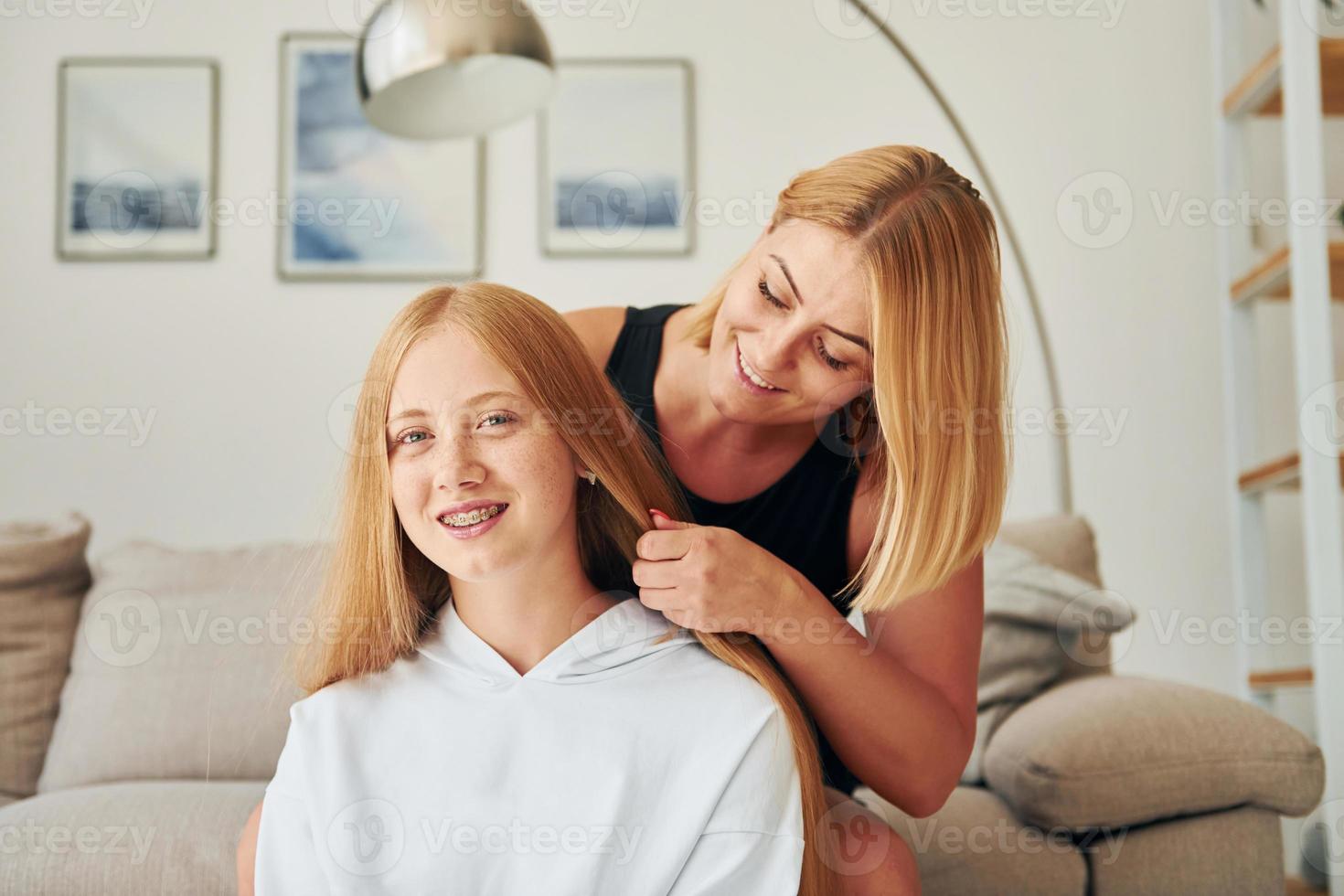 padre ayudando con el cabello. una adolescente con su madre está en casa durante el día foto