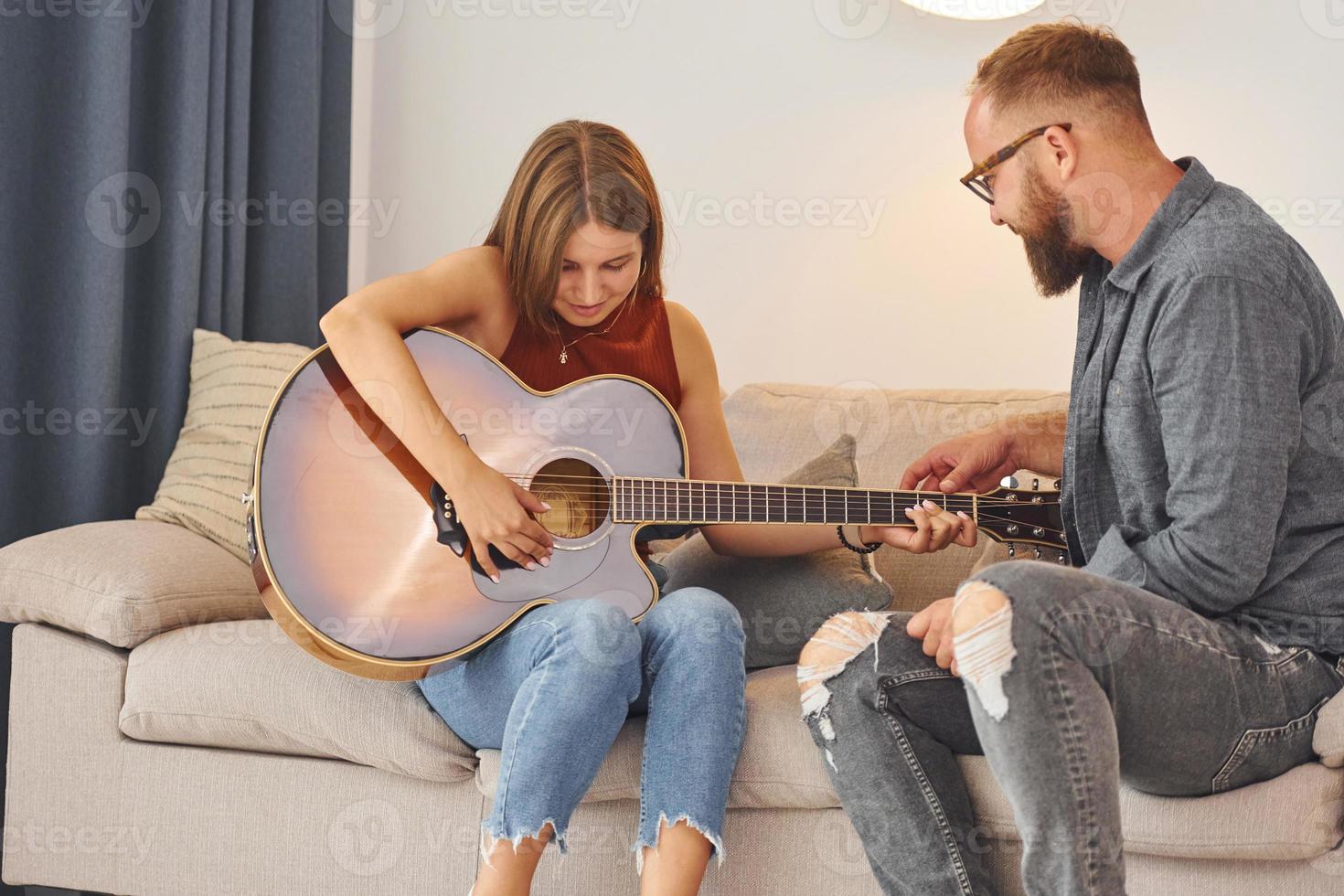 Guitar teacher showing how to play the instrument to young woman photo