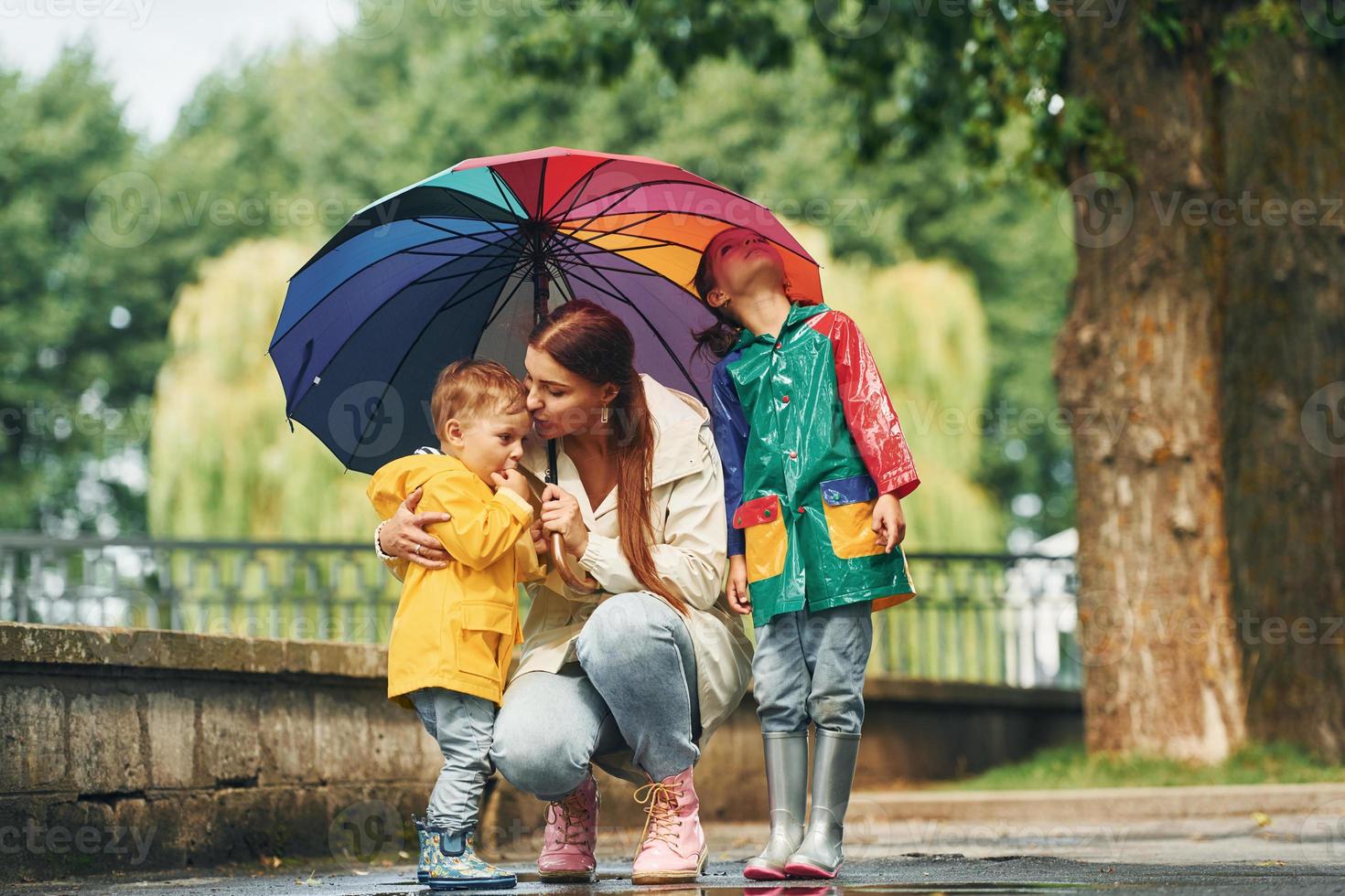 Mother with her little son and daughter have a walk outdoors in the park after the rain photo