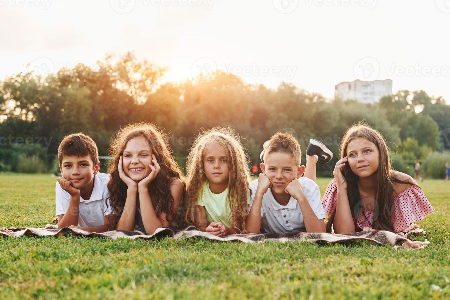 vista frontal. grupo de niños felices está al aire libre en el campo deportivo durante el día foto