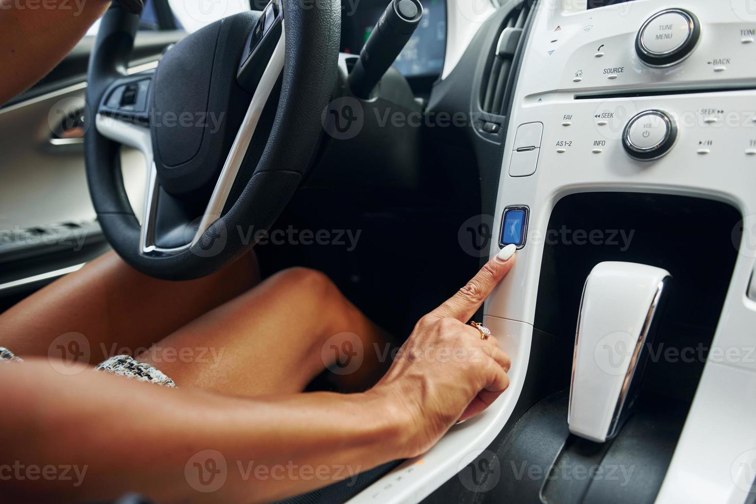 Close up view of front control panel. Woman in casual clothes is sitting in her automobile at daytime photo