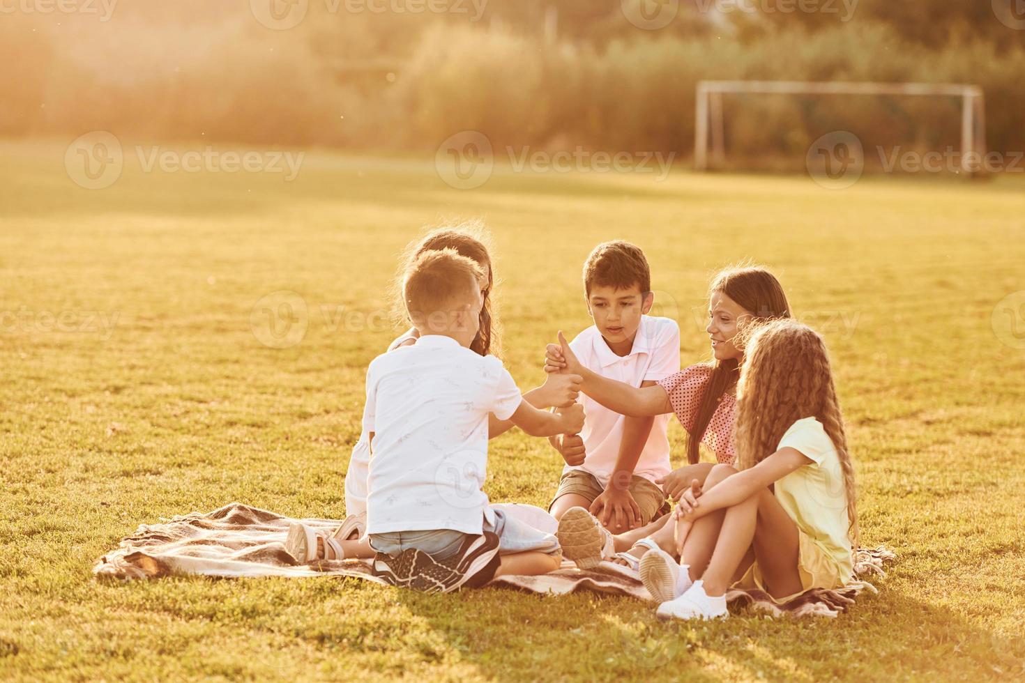Beautiful sunlight. Group of happy kids is outdoors on the sportive field at daytime photo