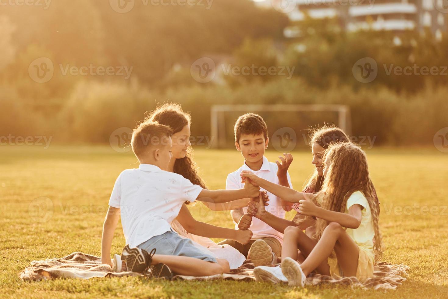Communicating with each other. Group of happy kids is outdoors on the sportive field at daytime photo