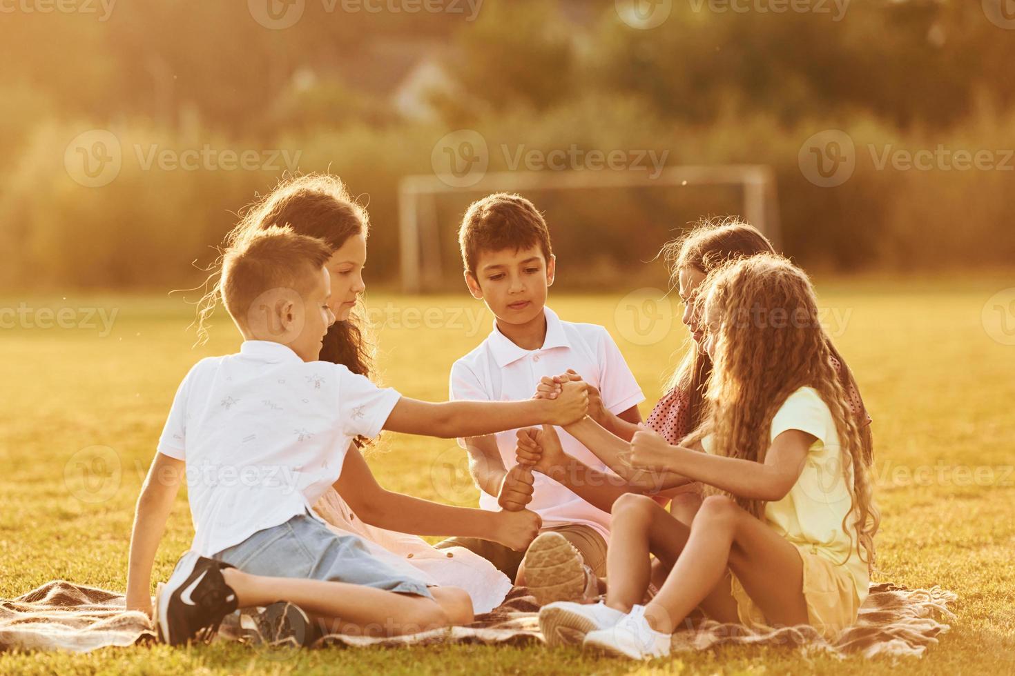 Communicating with each other. Group of happy kids is outdoors on the sportive field at daytime photo