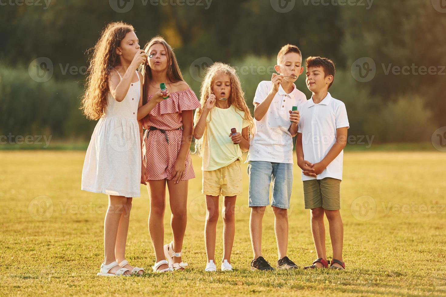 Beautiful sunlight. Group of happy kids is outdoors on the sportive field at daytime photo