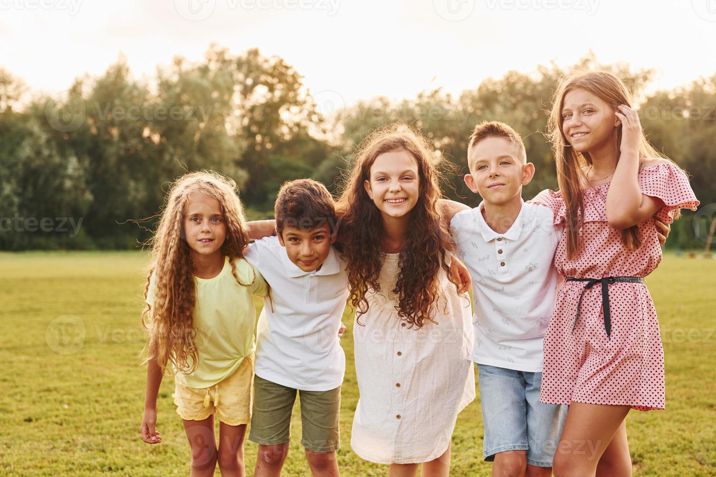 Having fun. Group of happy kids is outdoors on the sportive field at daytime photo