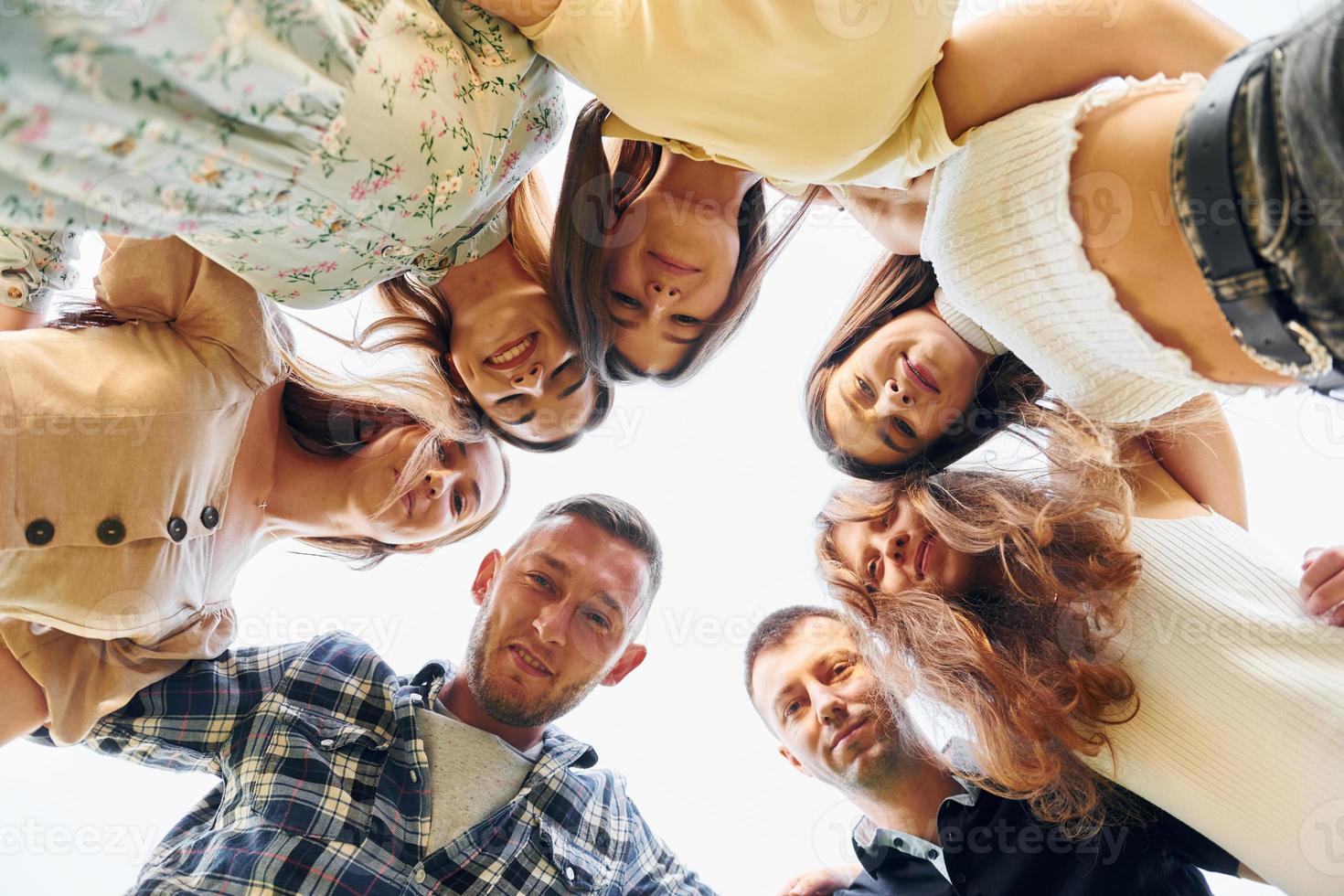 View from below of young positive people that looking down photo