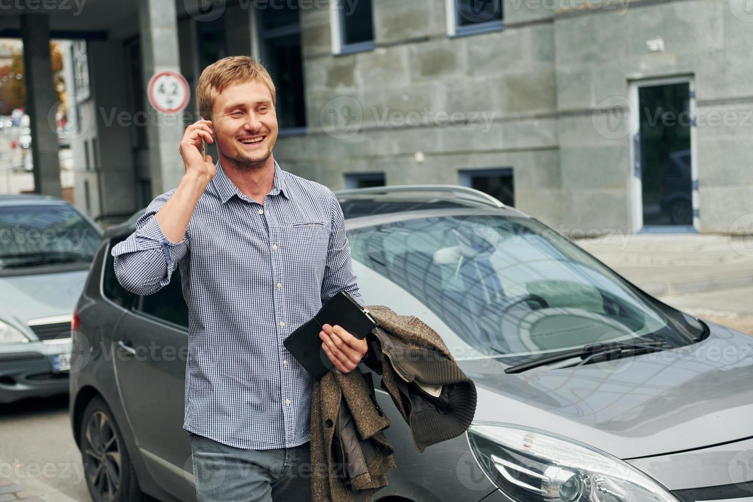 Talking by phone. Man having a walk outdoors in the city at daytime photo