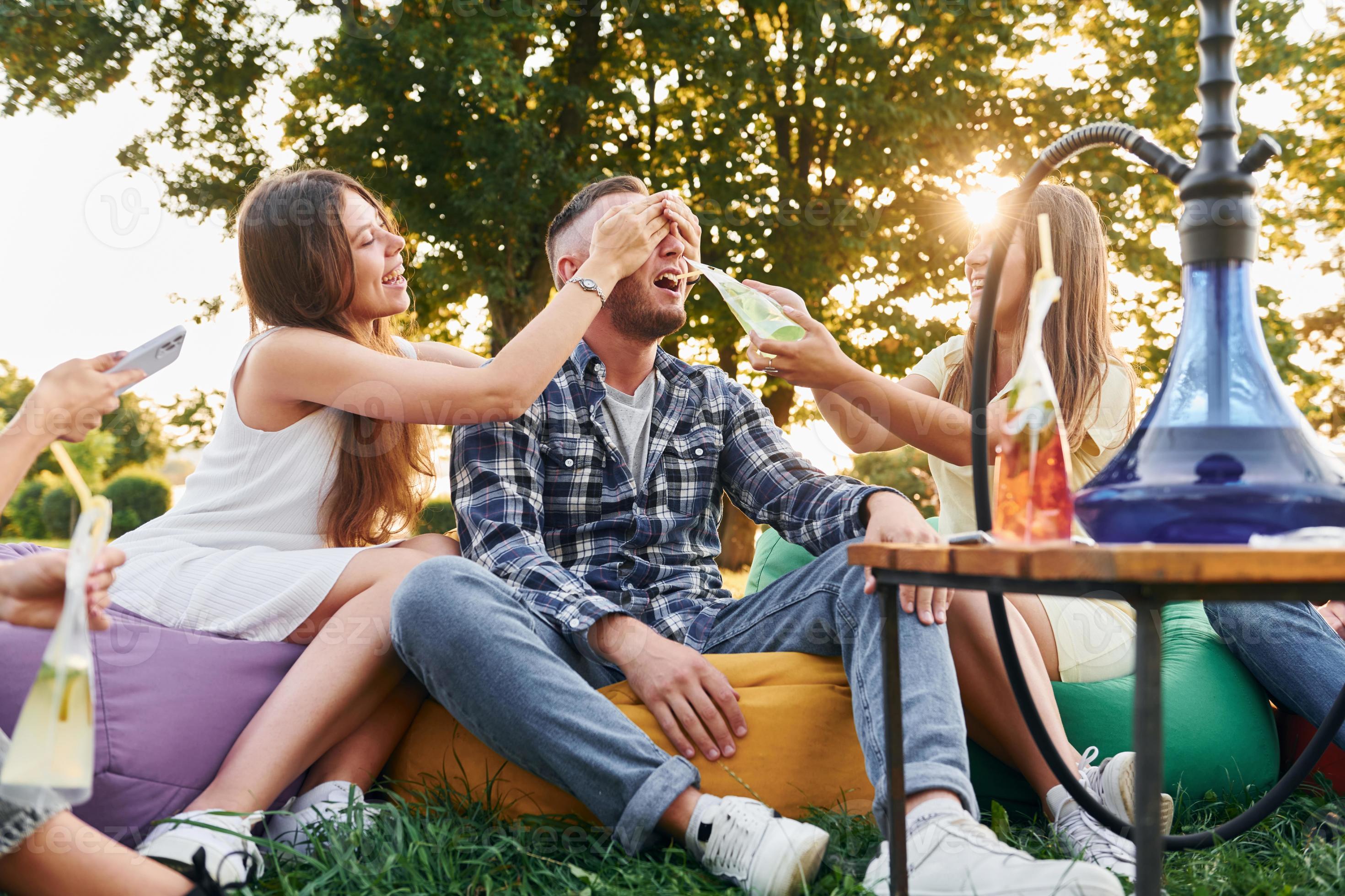 Drinking game. Group of young people have a party in the park at summer