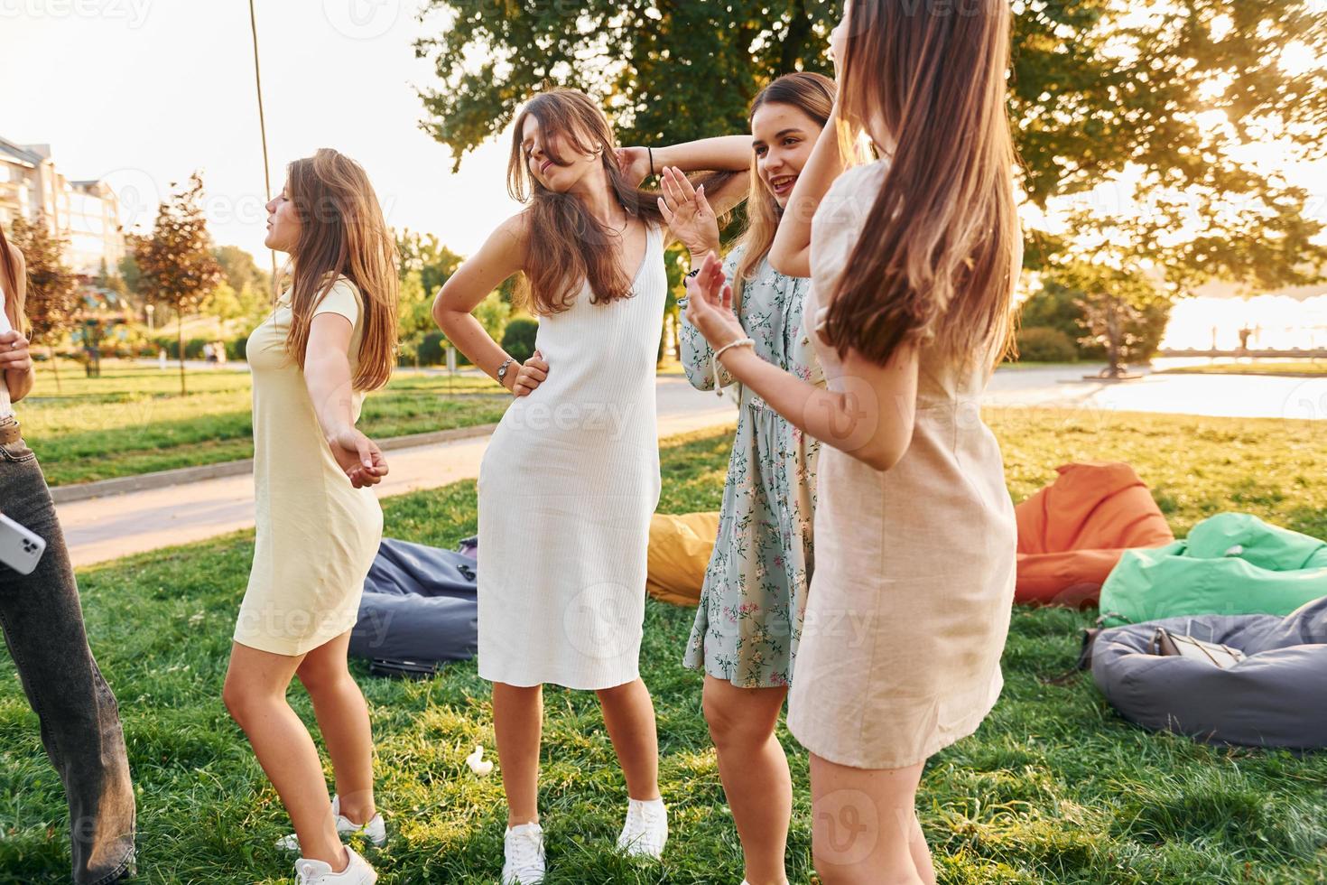 In different stylish clothes. Group of young people have a party in the park at summer daytime photo