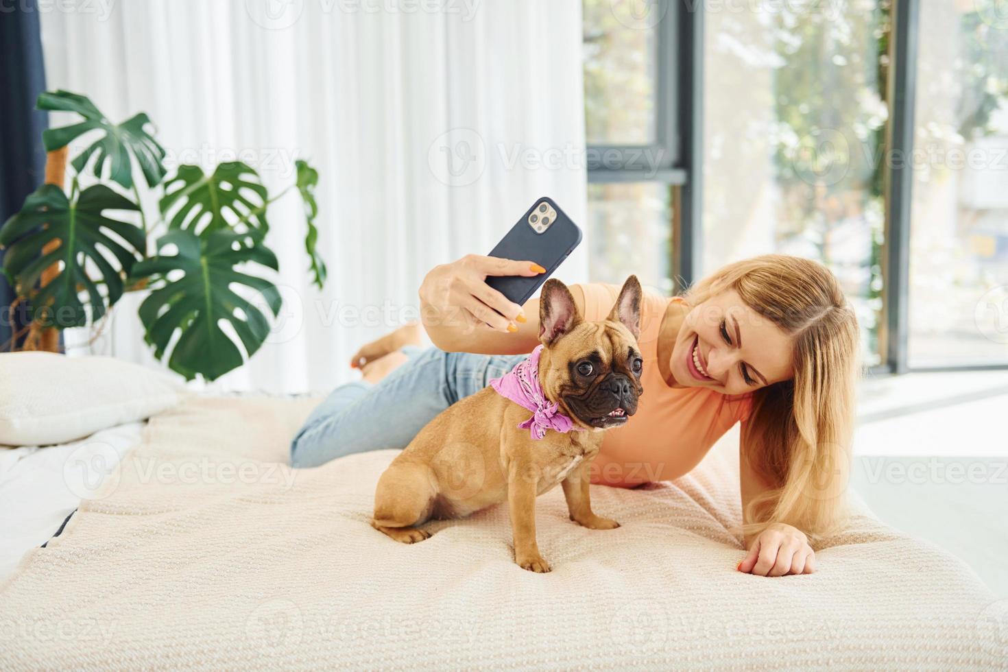 Doing selfie. Woman with pug dog is at home at daytime photo