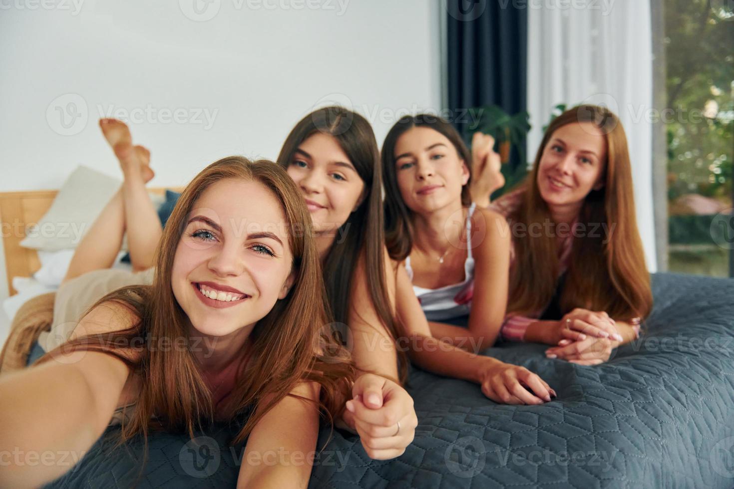 Making selfie by using phone. Group of happy women that is at a bachelorette party photo