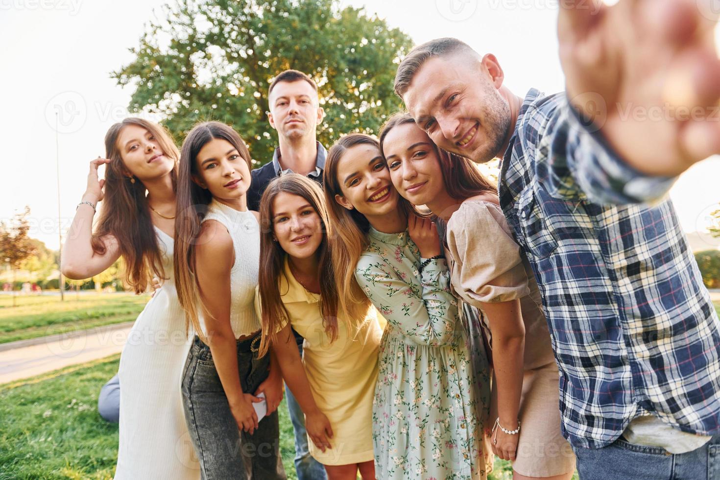 tomando una autofoto. grupo de jóvenes tienen una fiesta en el parque durante el día de verano foto