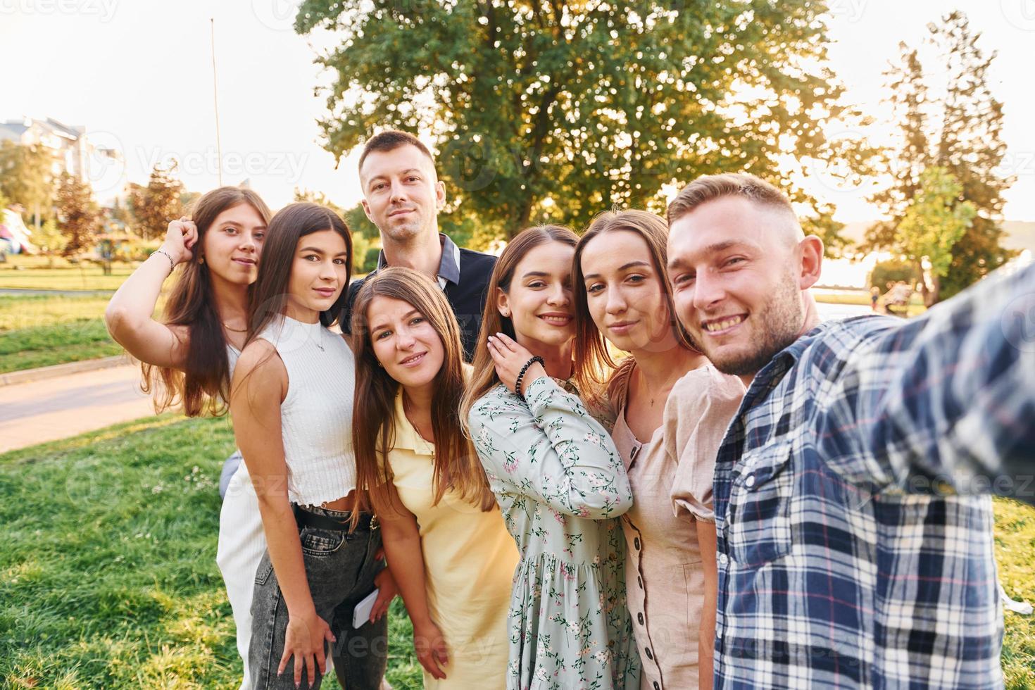 tomando una autofoto. grupo de jóvenes tienen una fiesta en el parque durante el día de verano foto