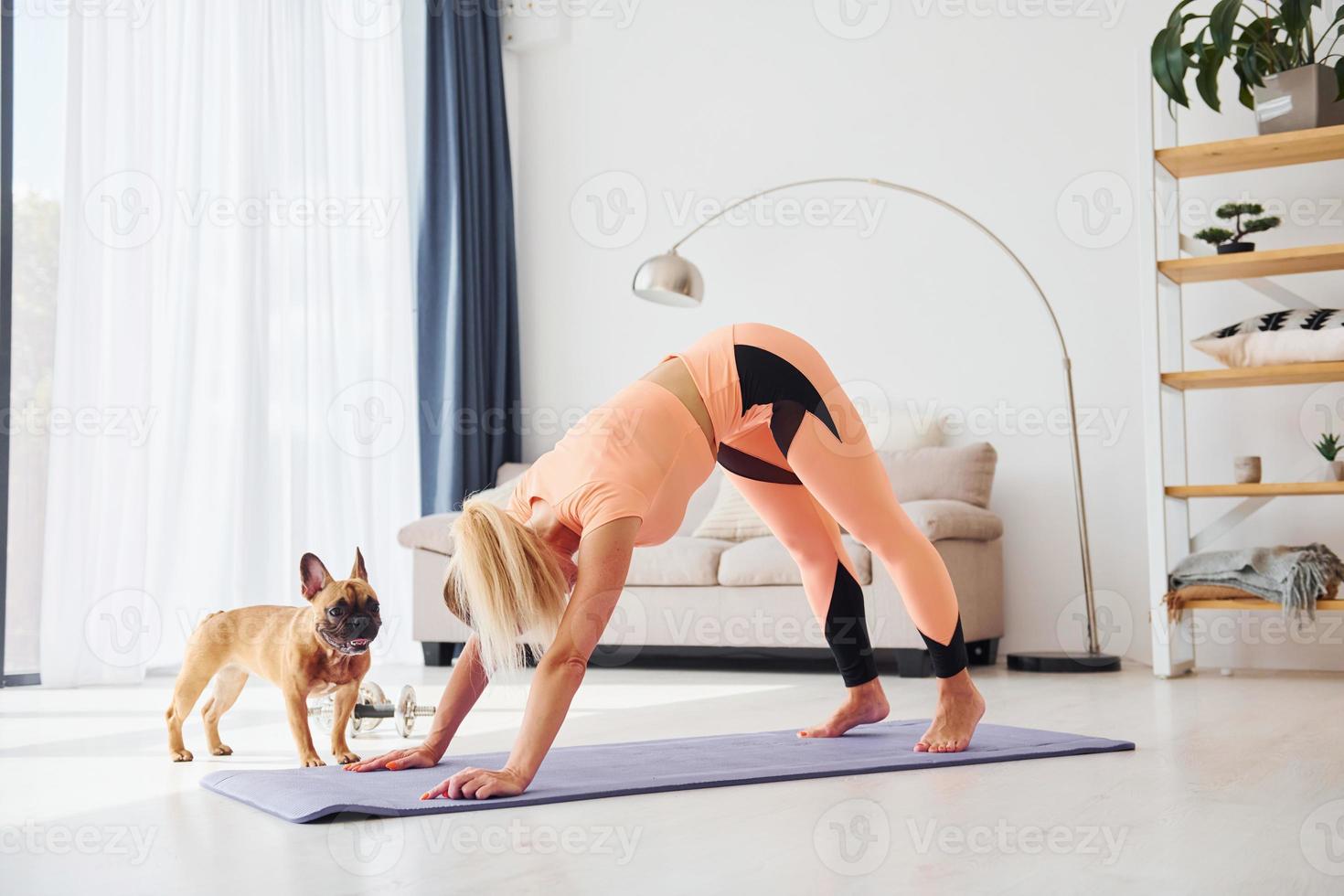 Woman in yoga clothes with pug dog is at home at daytime photo