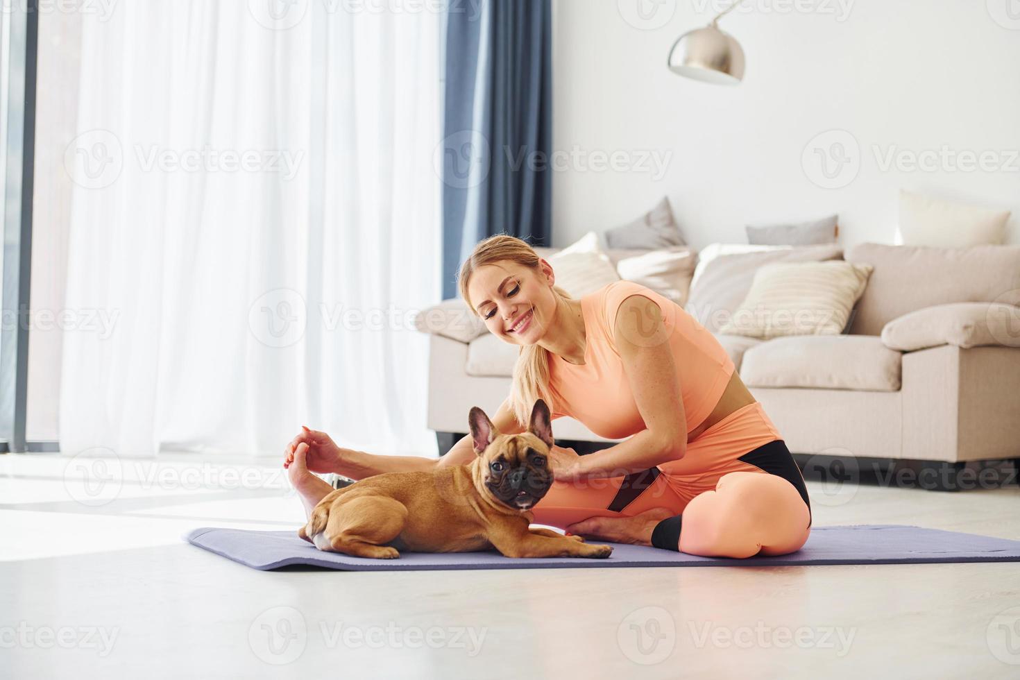 Yoga time. Woman with pug dog is at home at daytime photo