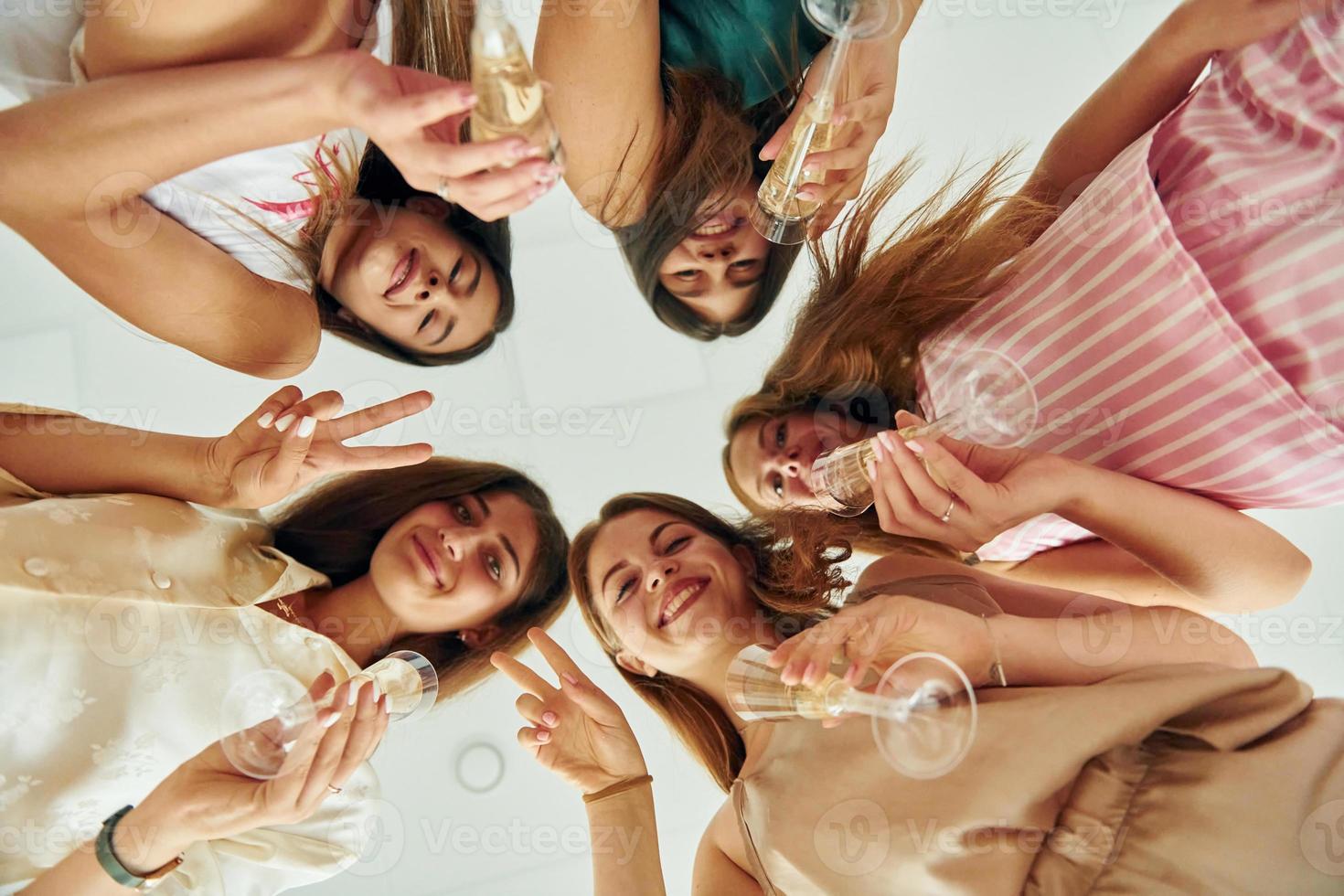 Holding drinks and looking down. Group of happy women that is at a bachelorette party photo