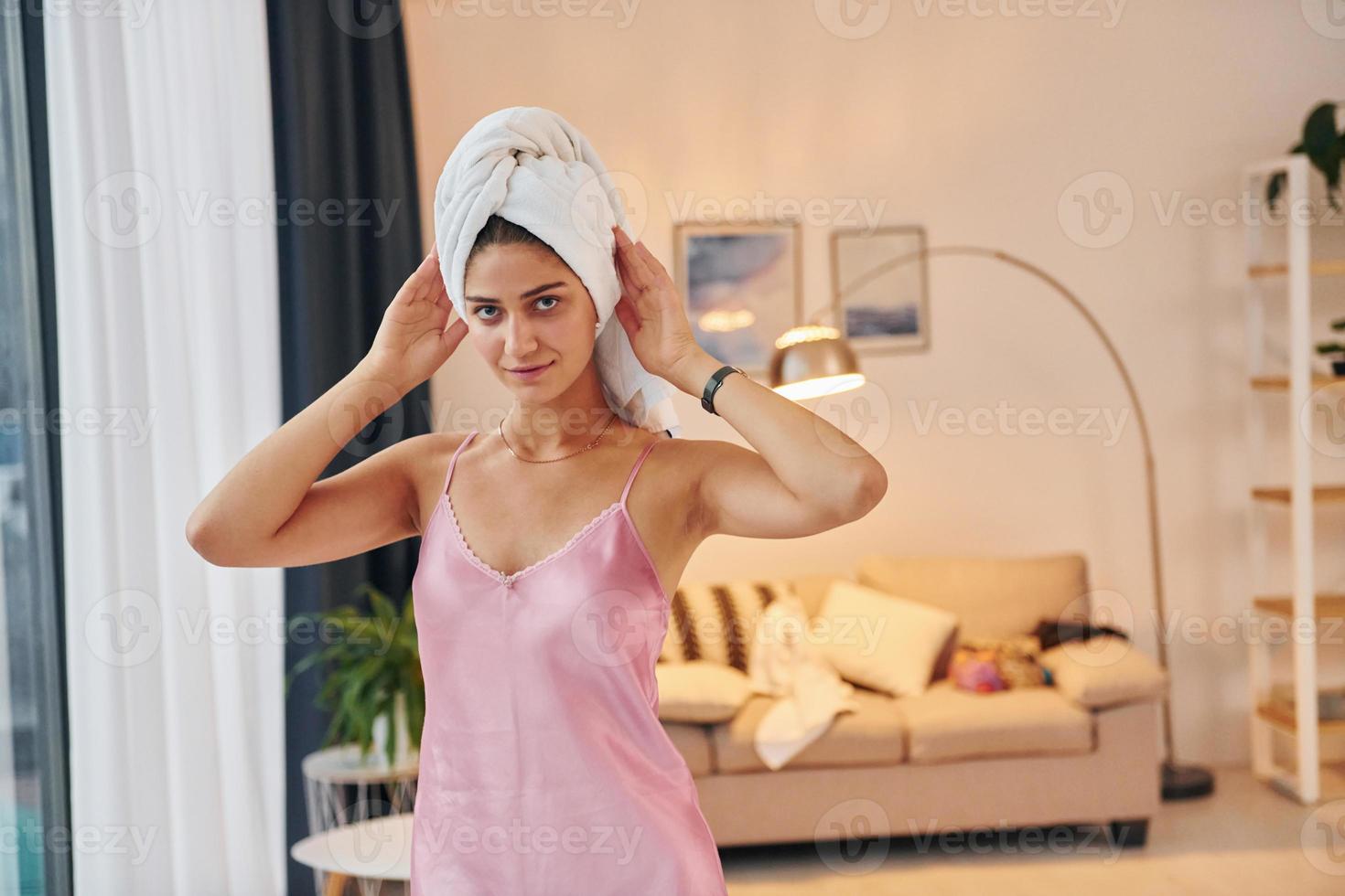 Young woman with white towel on head and in nightwear is indoors photo