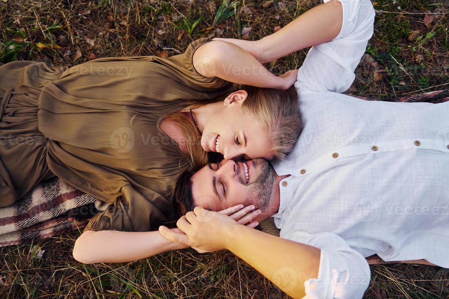 Happy couple is outdoors laying down on the ground photo