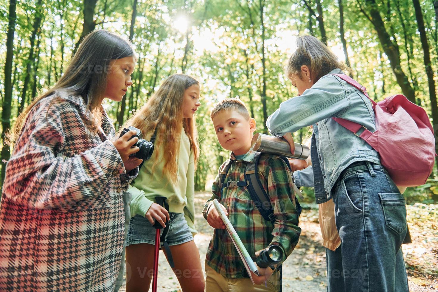 Standing together. Kids in green forest at summer daytime together photo